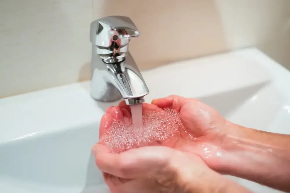 Person checking a bathroom tap with no hot water in a London home